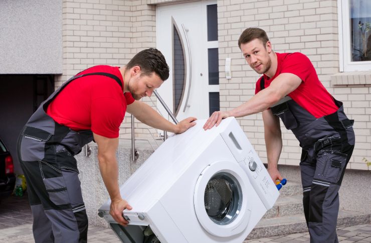 Two men in overalls are positioned with a washing machine, highlighting their laundry repair service in Houston, TX.