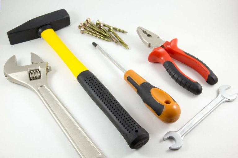 Various hand tools such as wrenches, pliers, and nails laid out on a table for easy access.